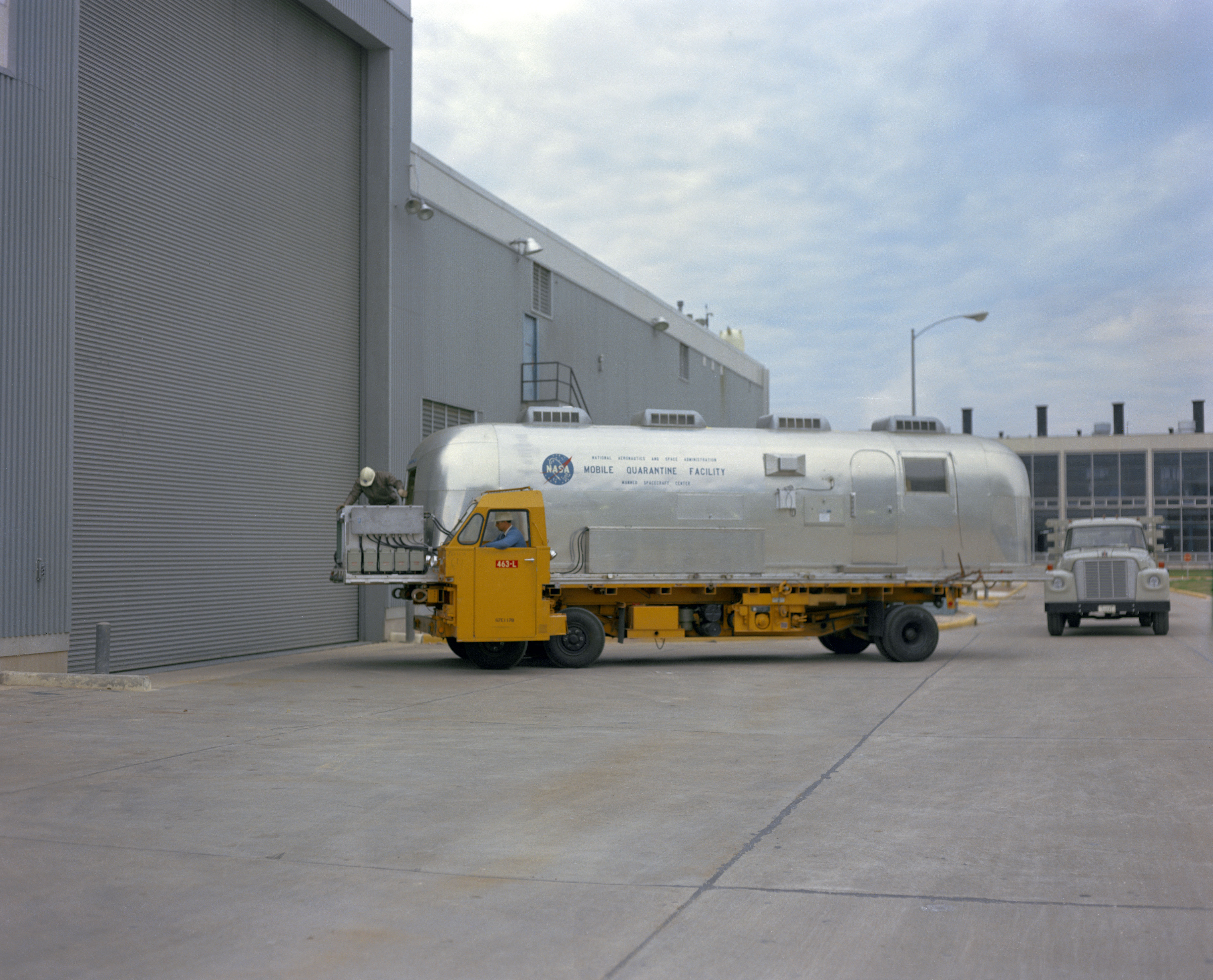 Workers truck the Mobile Quarantine Facility (MQF) into the Space Environment Simulation Laboratory (SESL) at the Manned Spacecraft Center, now NASA’s Johnson Space Center in Houston