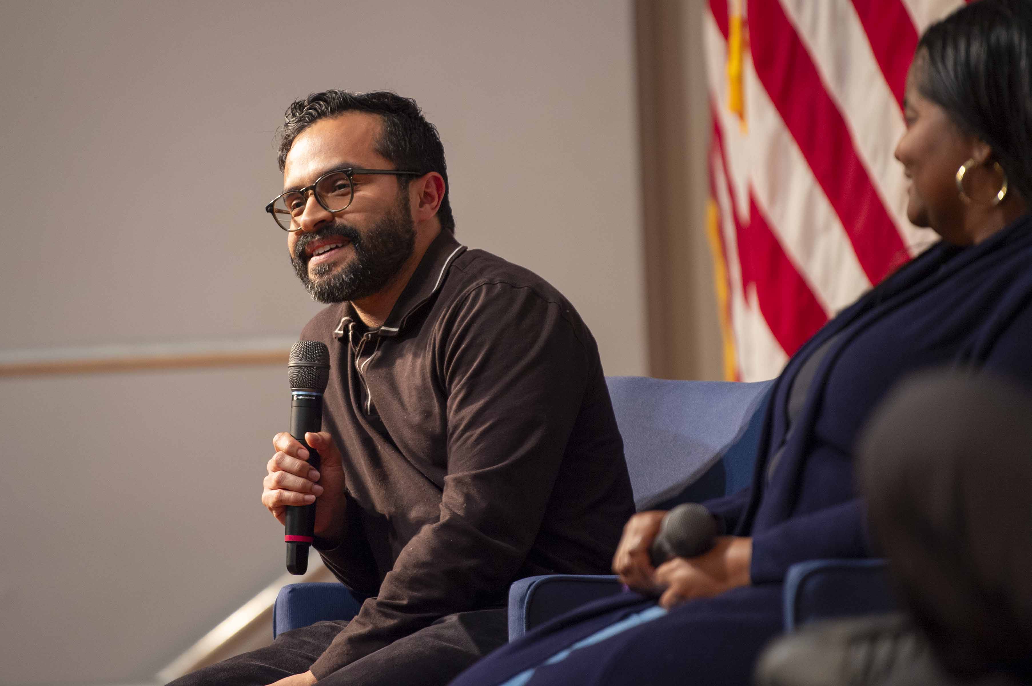 NASA Stennis mechanical engineer Armando Delgado, seated on the left, wearing a long-sleeve brown shirt, speaks to audience members about his field of study