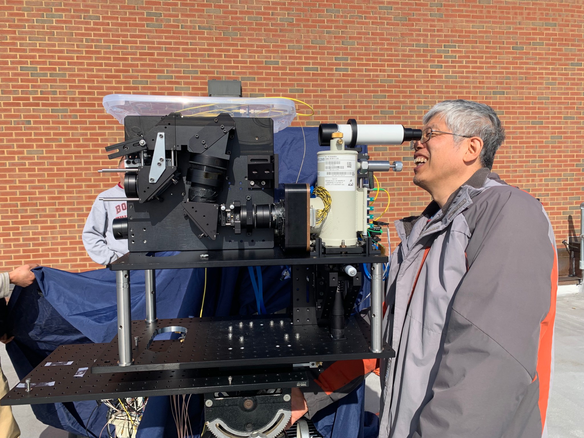 an engineer looks into an eyepiece connected to a large lidar instrument.