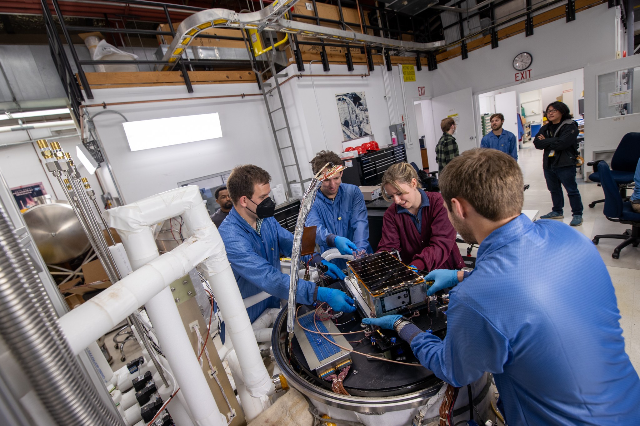 This photograph shows four people preparing the BurstCube satellite for thermal vacuum testing.