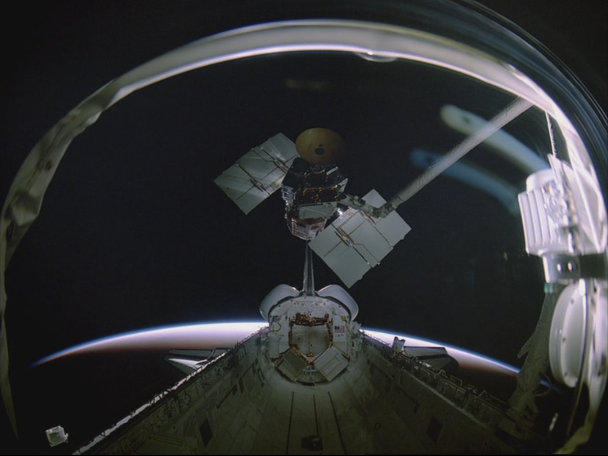 Terry J. Hart lifts the repaired Solar Max out of Challenger’s payload bay