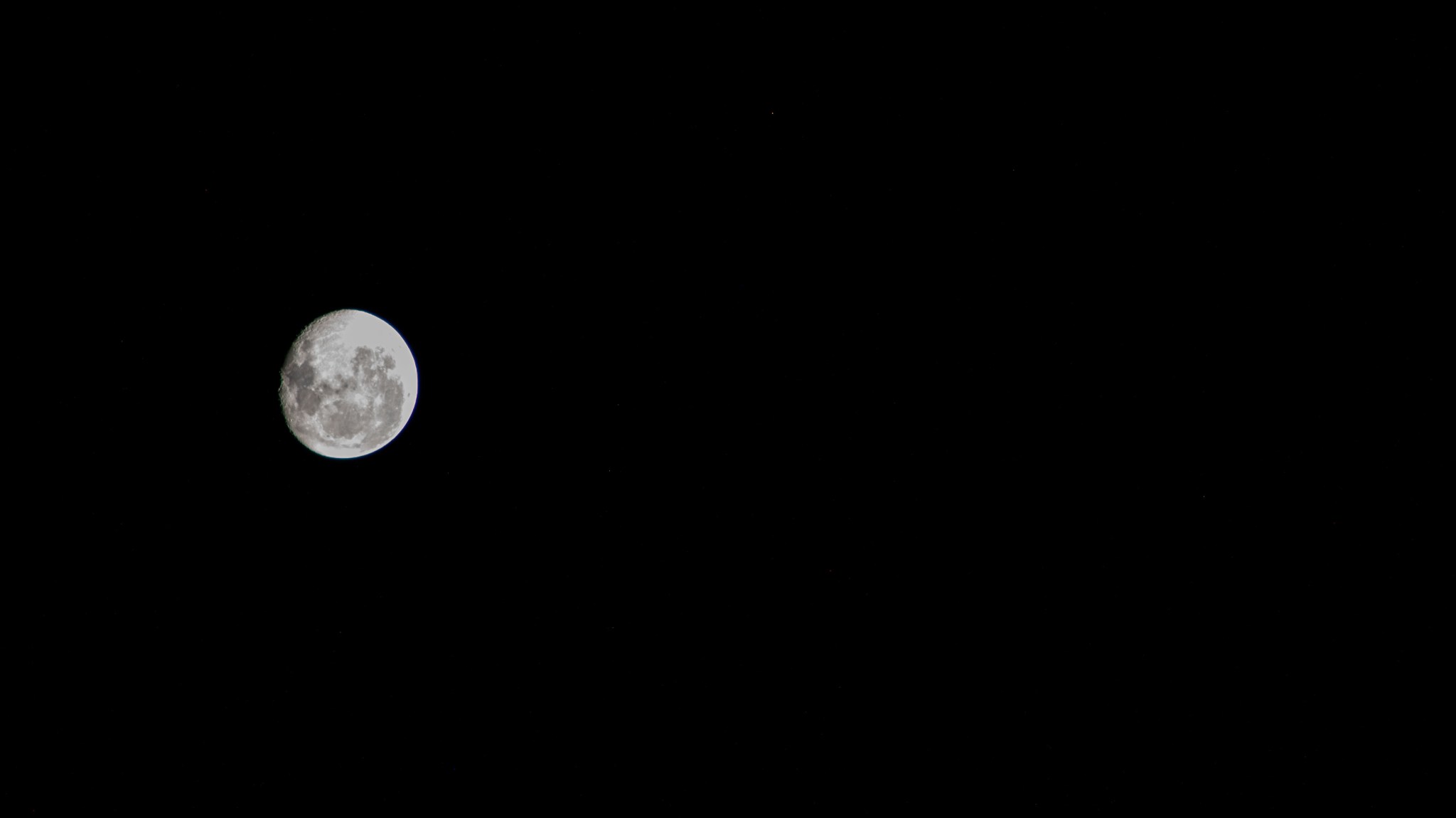 The silvery waning gibbous moon against the darkness of space, as seen from the International Space Station.