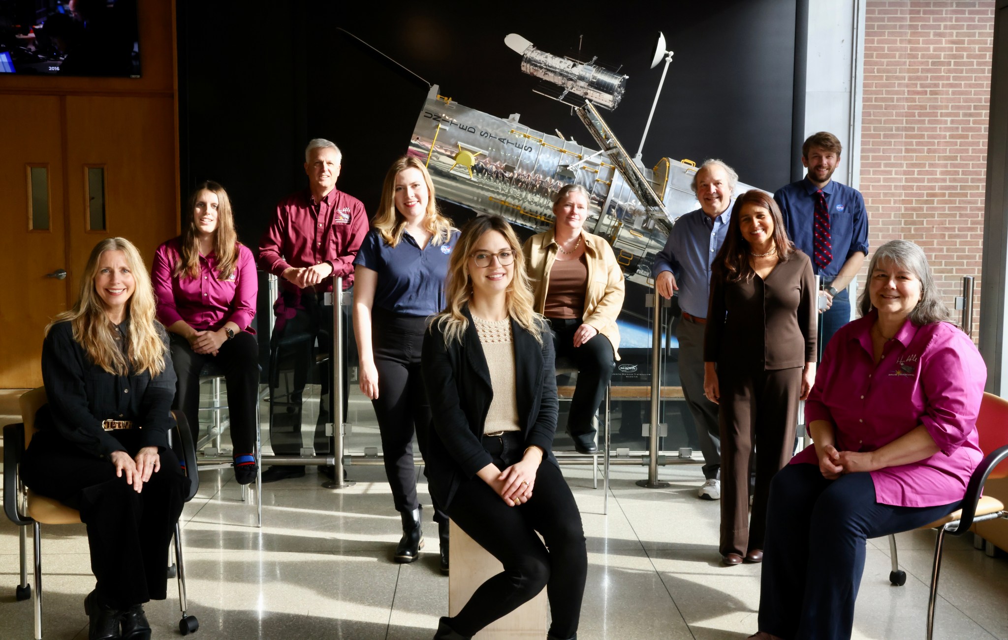 The Hubble outreach team smiles for a photo in front of the Hubble model at NASA Goddard. 