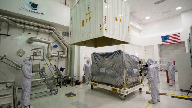 At JPL on May 17, members of the Roman Coronagraph Instrument team use a crane to lift the top portion of the shipping container that the instrument was stored in for its journey to NASA’s Goddard Space Flight Center.