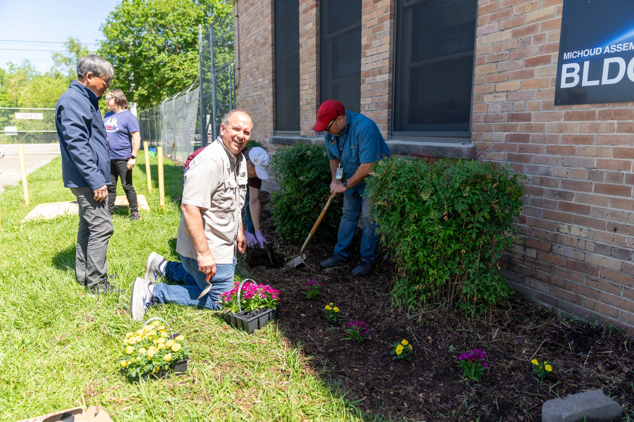 Michoud Environmental Officer Ben Ferrell plants purple and gold flowers in the freshly weeded landscaping next to Building 101.