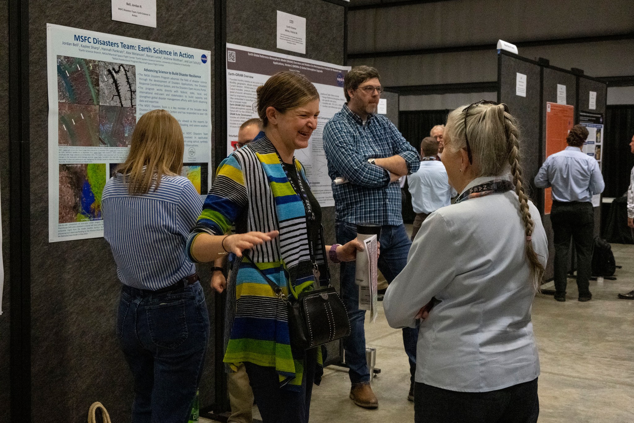 Hannah Pankratz, center, NASA Postdoctoral Program fellow in the Earth Science branch, talks about her poster with Mitzi Adams, assistant manager of the Heliophysics and Planetary Science branch of the Science and Technology Office, during the 2024 Science, Technology, and Engineering Jamboree and Poster Expo. Pankratz’s poster represented the Disaster Team at Marshall, highlighting some of the center’s response work and recent research.