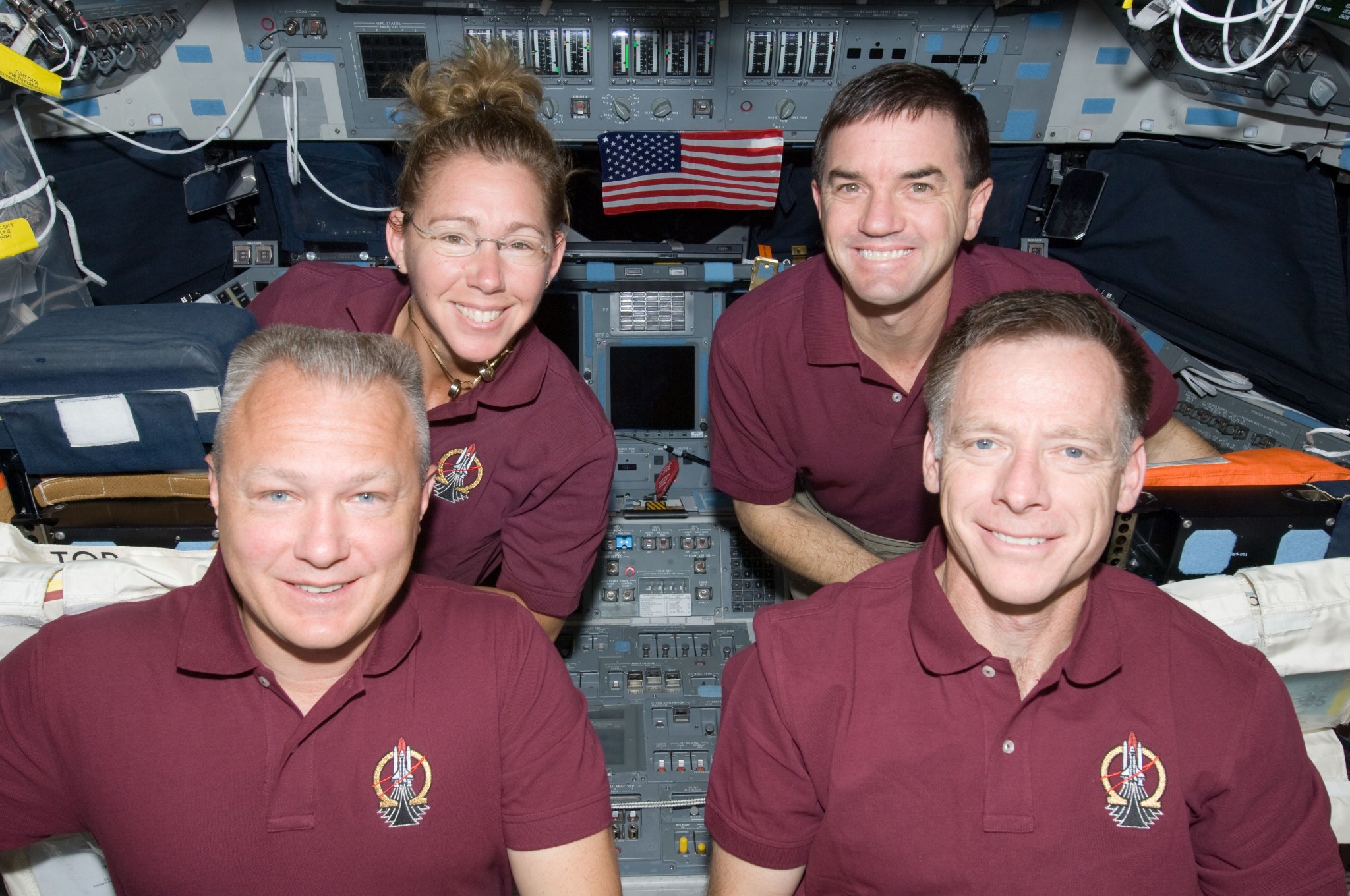 Astronauts Chris Ferguson, Doug Hurley, Sandy Magnus, and Rex Walheim smile and pose with an American flag aboard Atlantis