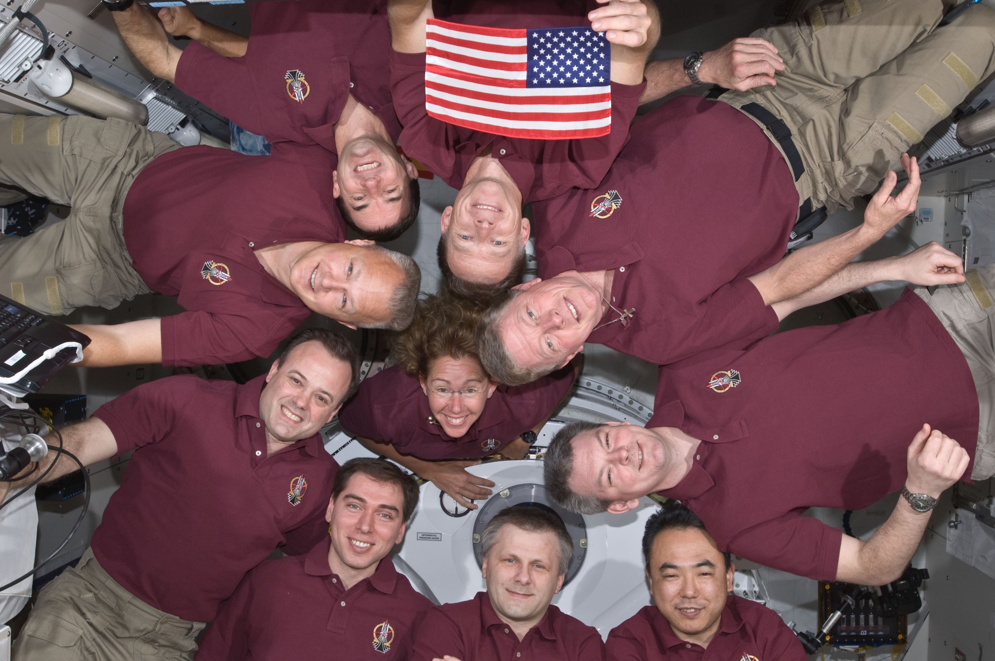 Astronauts aboard the space station pose in a circle with an American flag