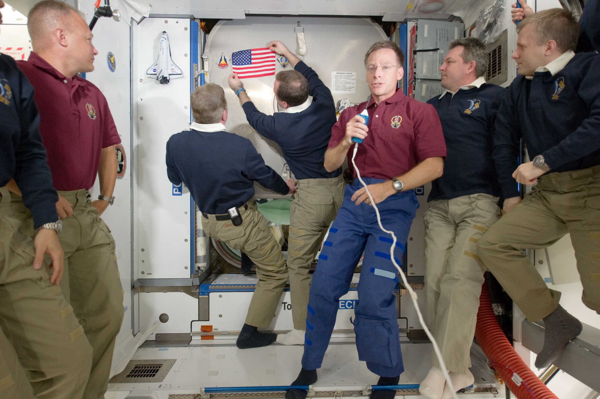 Astronauts aboard the space station placing an American flag on a hatch