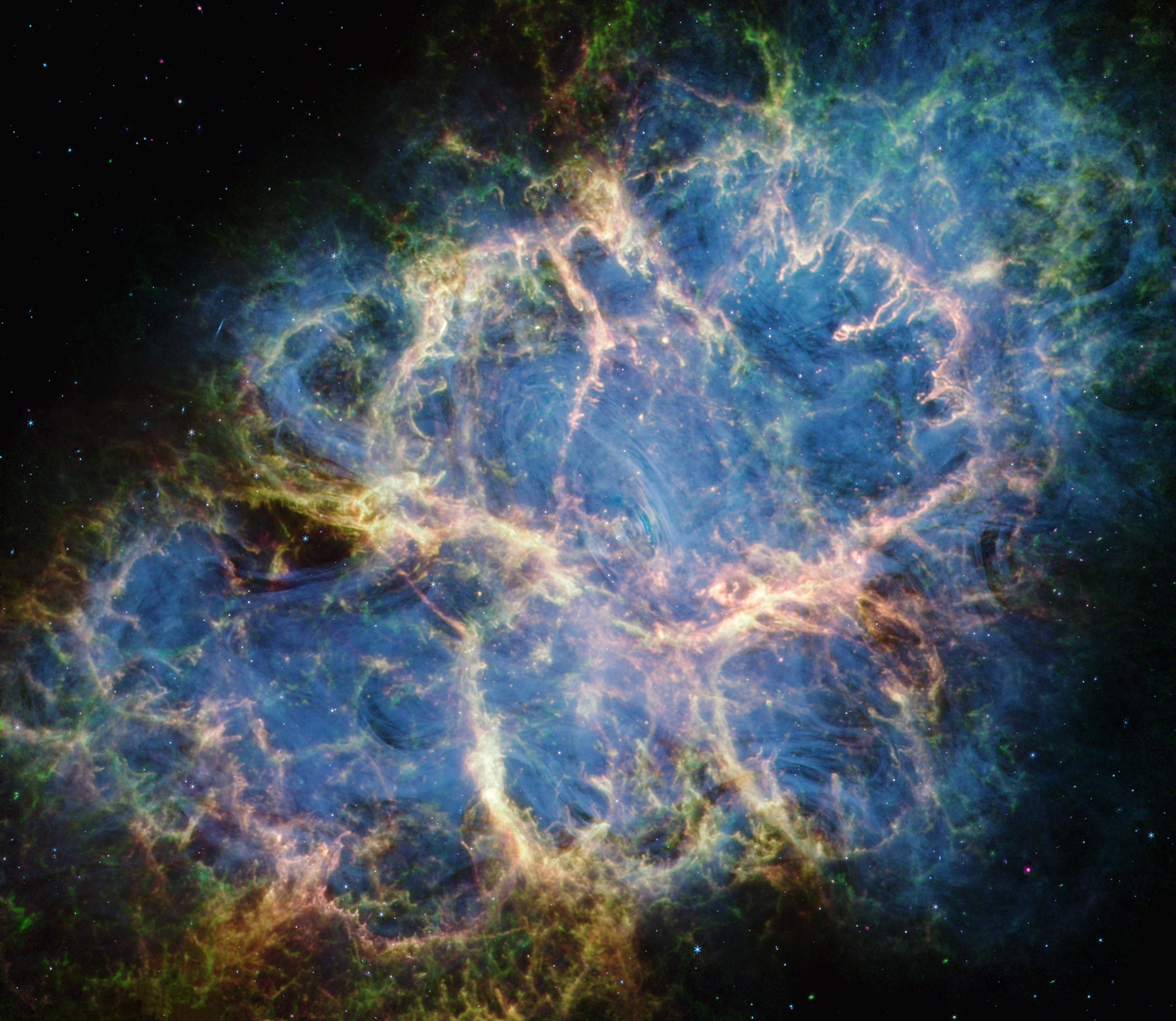 The Crab Nebula. An oval with complex structure extends from lower left to upper right against a black background. On the oval’s exterior lie curtains of glowing yellow and green fluffy material. Its interior shell shows large-scale loops of mottled filaments of yellow-white and green, studded with clumps and knots. Translucent thin ribbons of smoky blue lie within the remnant’s interior, brightest toward its center. The blue material follows different directions throughout, including sometimes sharply curving away from certain regions within the remnant. A faint, wispy ring of blue material encircles the very center of the nebula. Around and within the supernova remnant are many points of blue, green, purple, and white light.