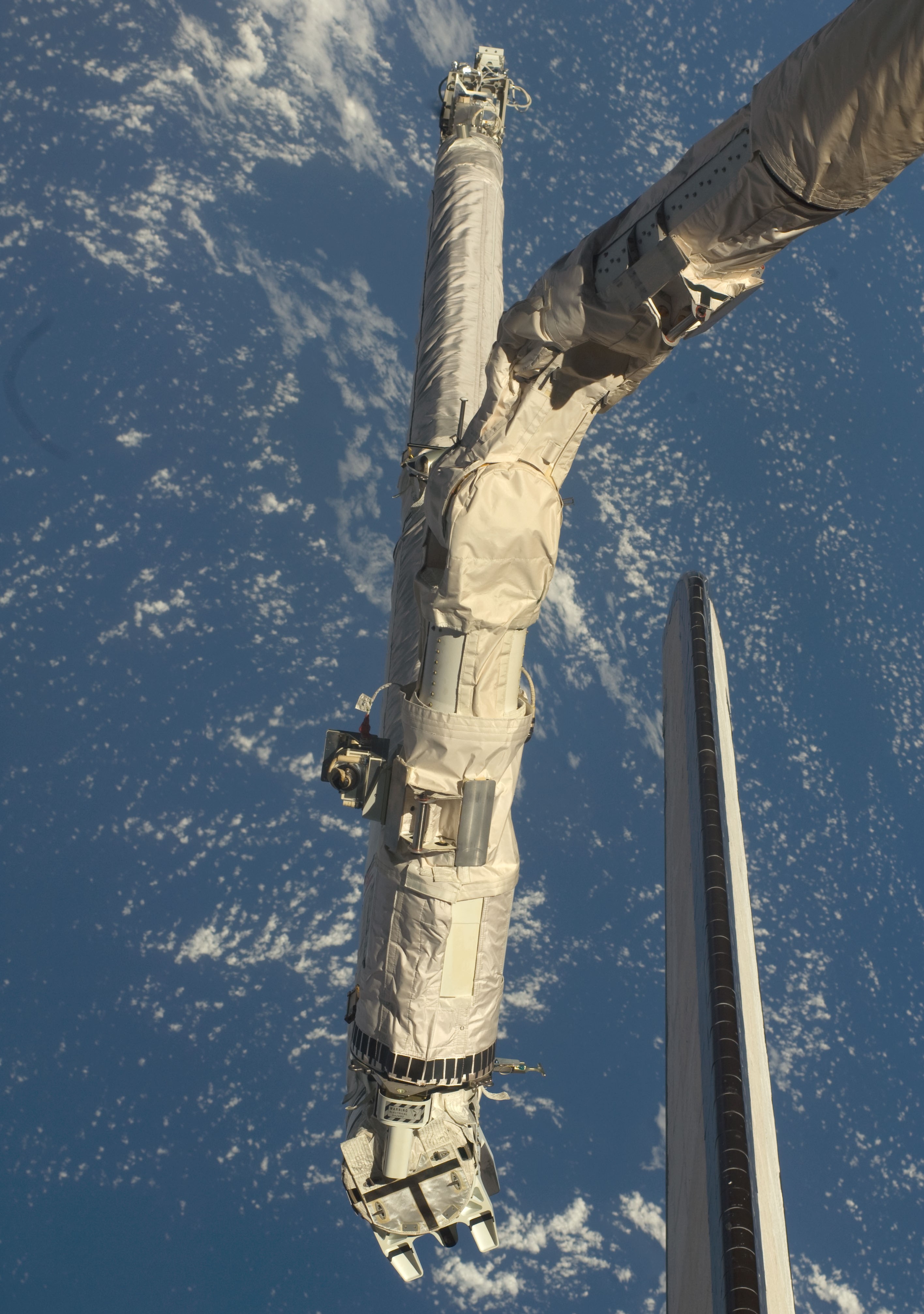 The shuttle’s robotic arm grapples the Orbiter Boom Sensor System for the late inspection of Endeavour’s heat shield