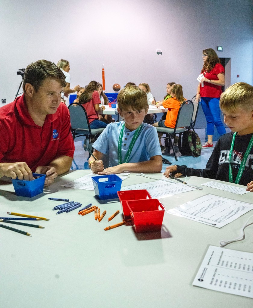 Christopher Sherman, the man in red shirt, conducts an activity with two Take Our Children to Work Day participants