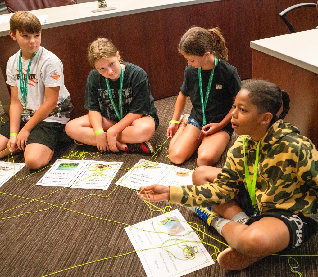 a small group of Take Our Children to Work Day participants sit on the floor during an acitivity