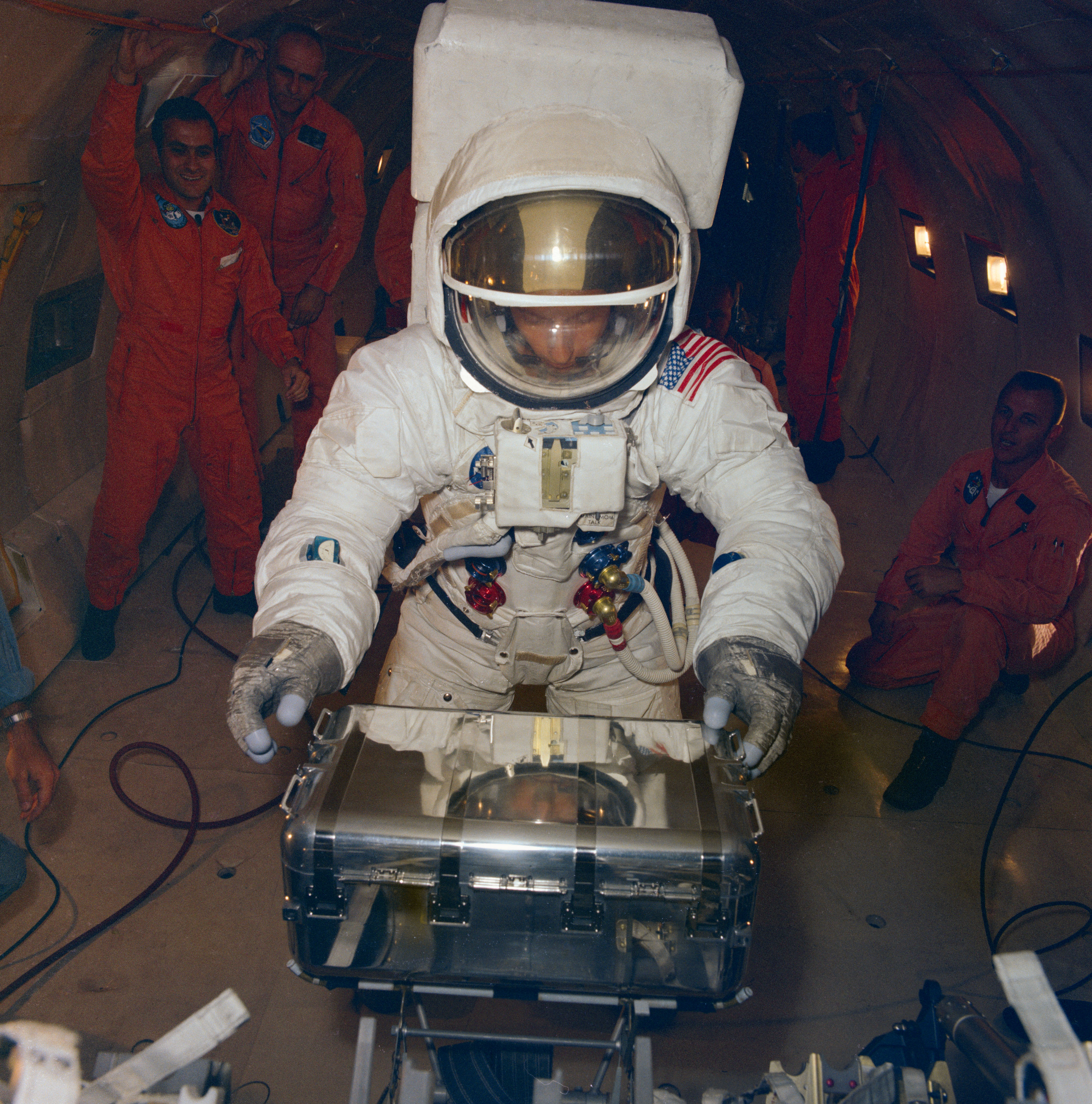 Conrad practices opening an Apollo Lunar Sample Return Container during simulated one-sixth gravity aboard a KC-135 aircraft