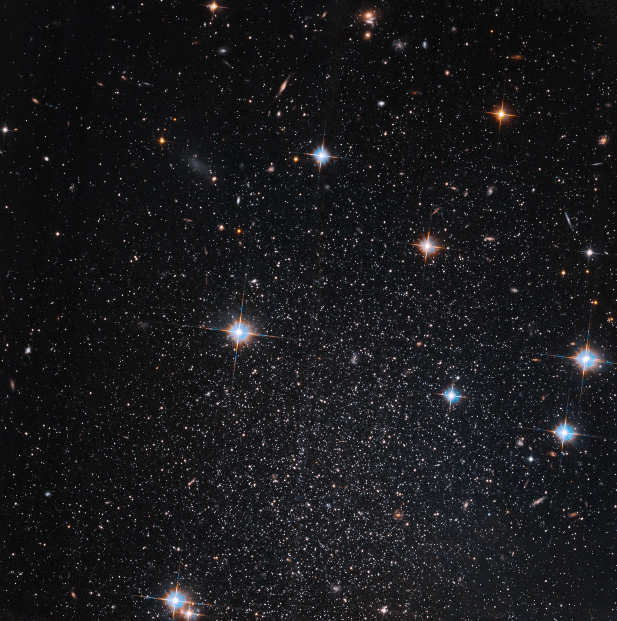 Several stars shine against black space. A few foreground stars with diffraction spikes throughout.