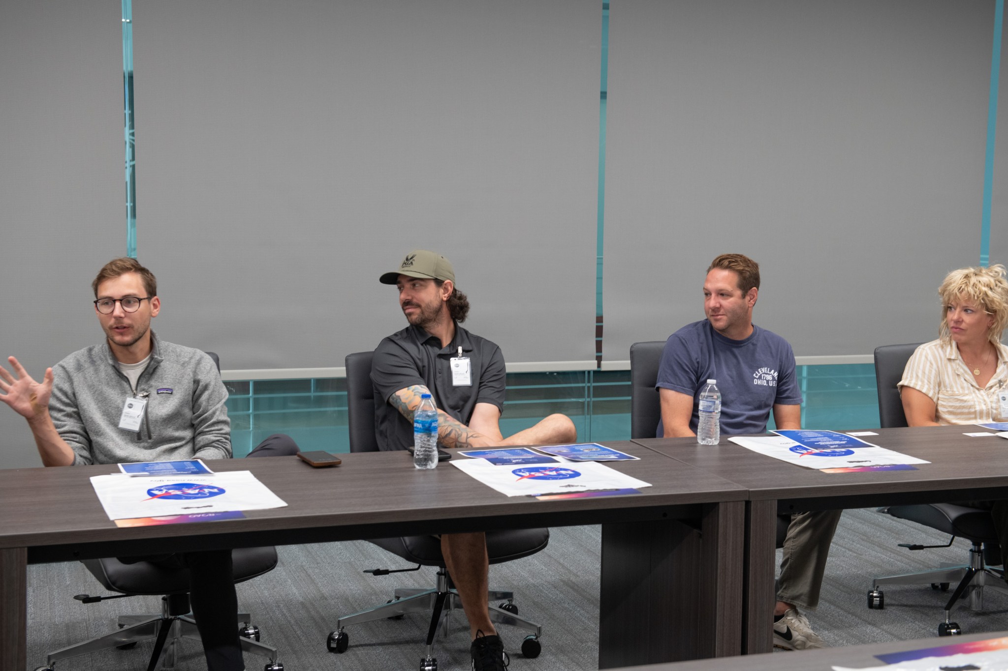 Four people sit behind a long table that contains information on NASA’s iconic logo.