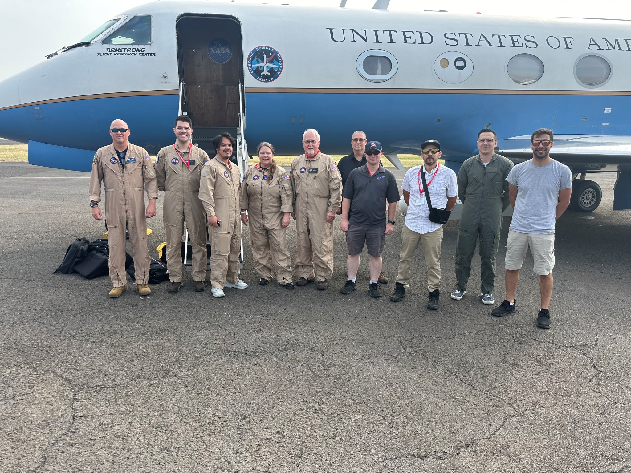 Ten people post in front of an aircraft.