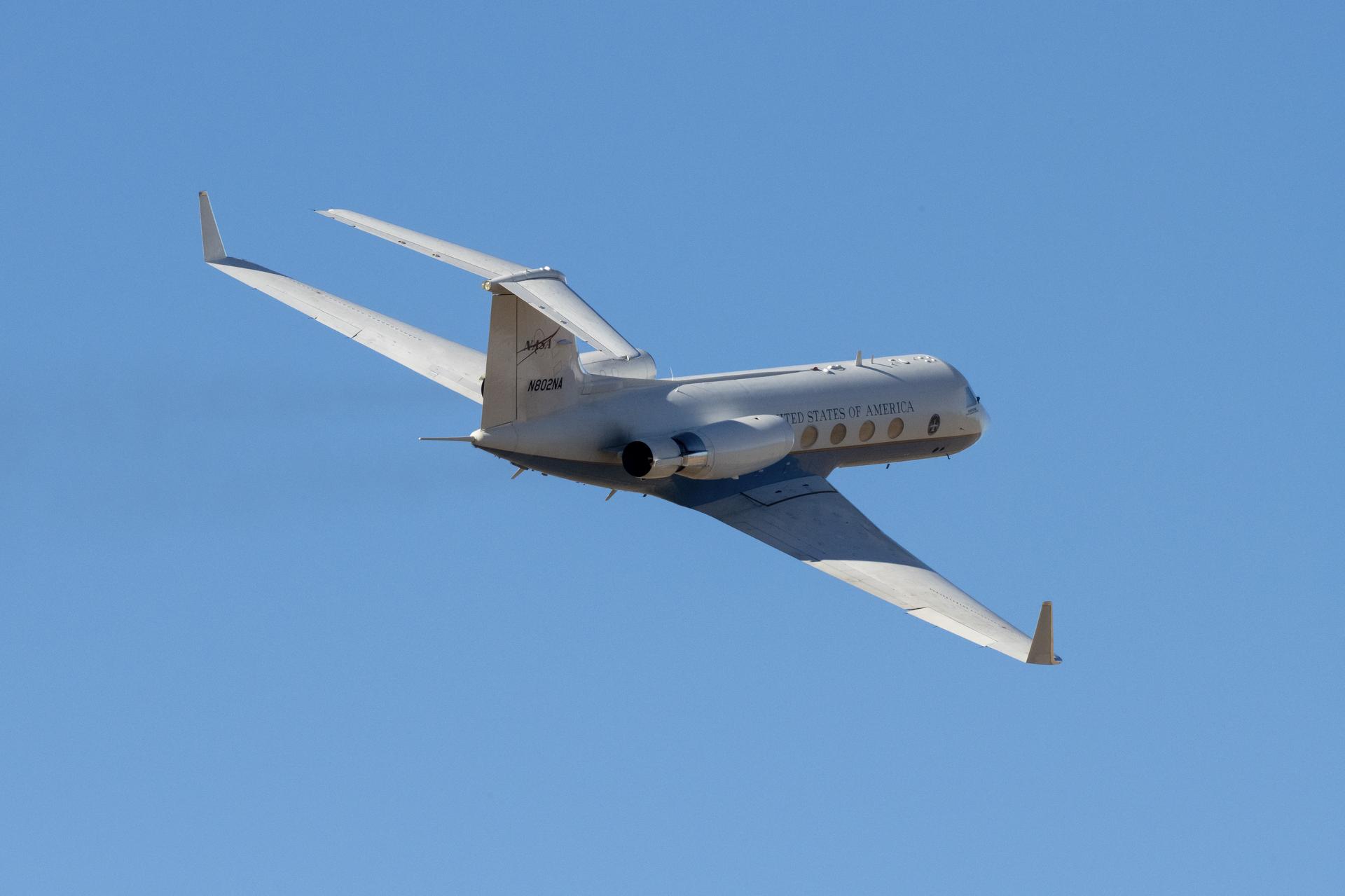 An aircraft in flight against a bright blue cloudless sky. 