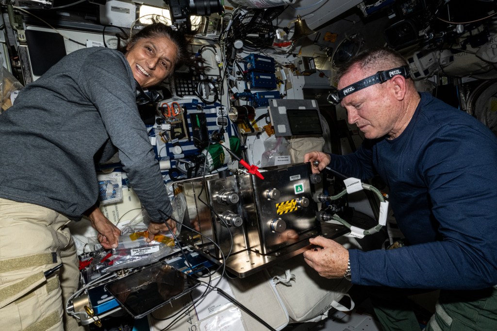 NASA's Boeing Crew Flight Test astronauts Suni Williams and Butch Wilmore prepare orbital plumbing hardware for installation inside the International Space Station’s bathroom, also known as the waste and hygiene compartment, located in the Tranquility module.