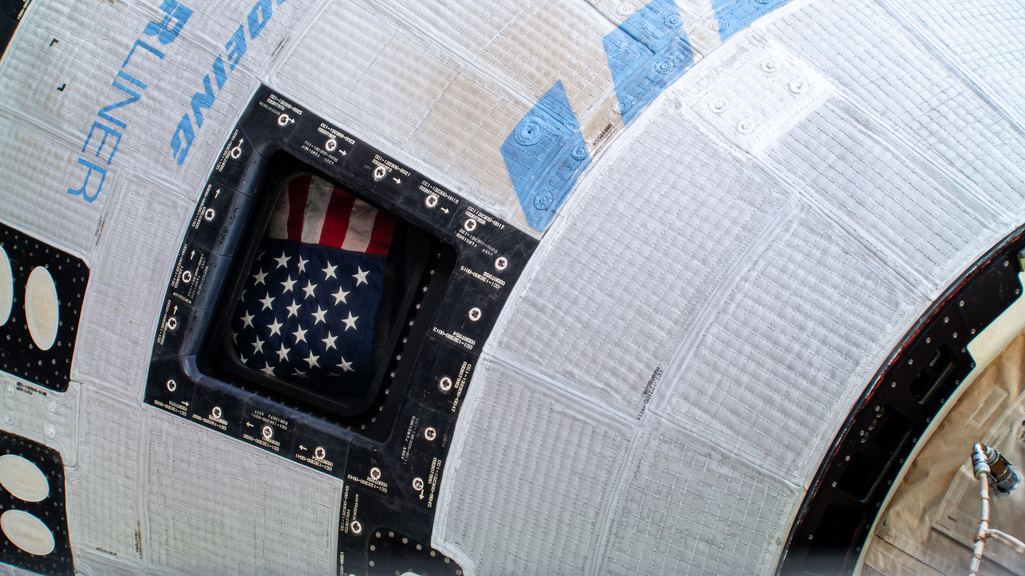 A picture of the American flag inside the window of Boeing's Starliner spacecraft at the International Space Station.