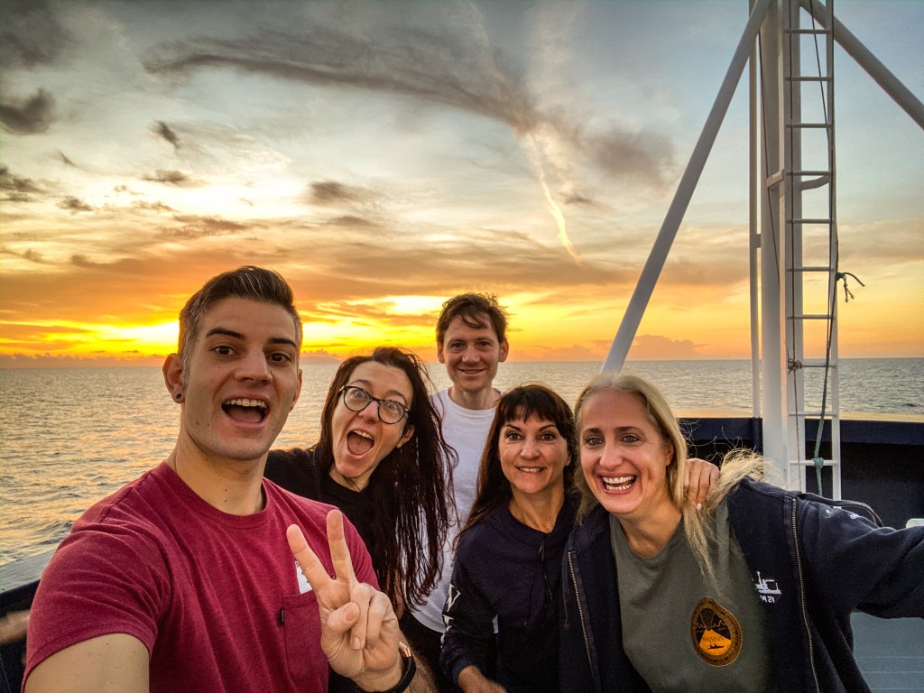 Filmmaker Mike Toillion takes a selfie, holding up a peace sign with members of the science team.