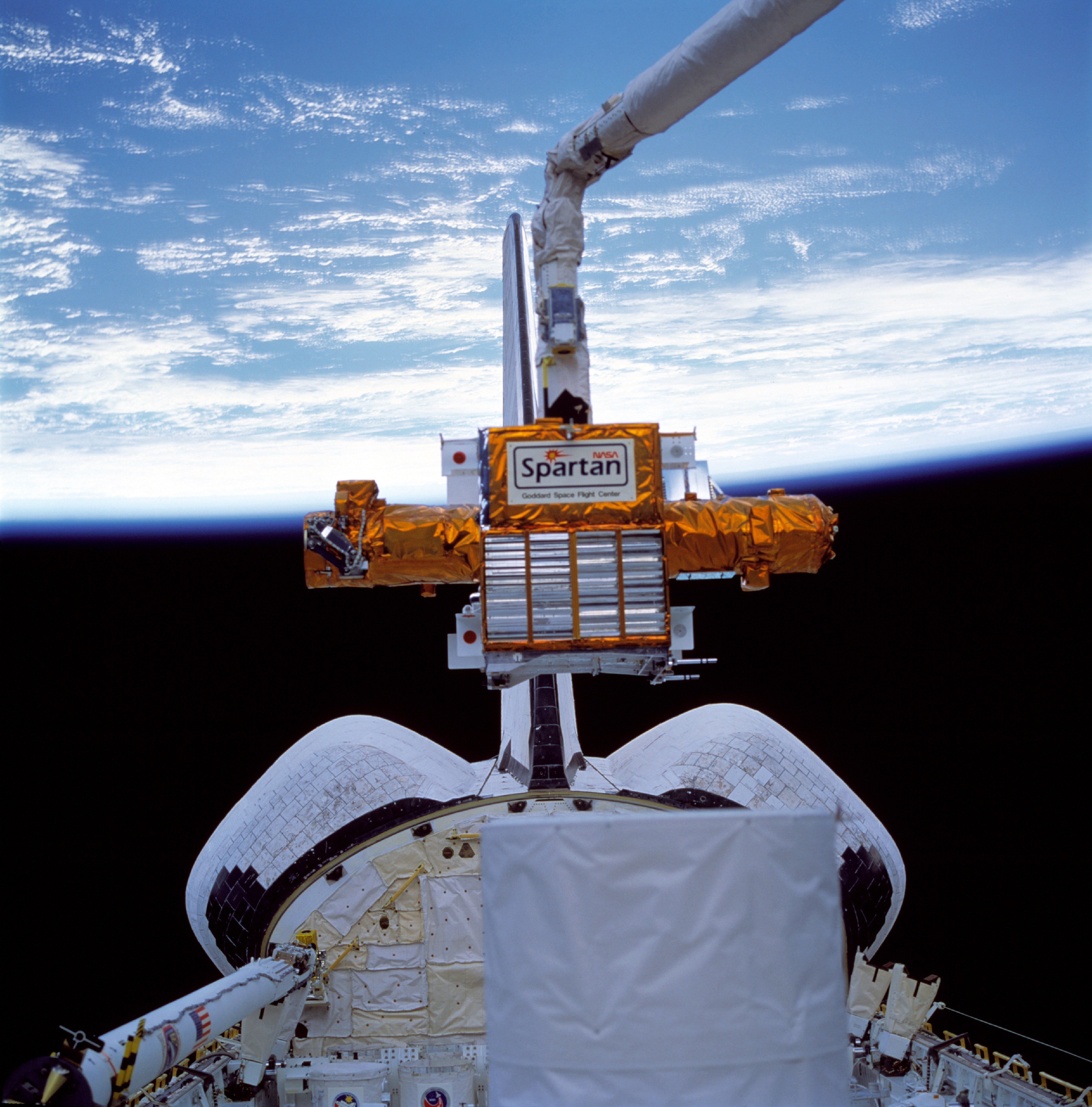 Astronaut Susan J. Helms lifts the Shuttle Pointed Autonomous Research Tool for Astronomy-201 (SPARTAN-201) out of Discovery’s payload bay prior to its release