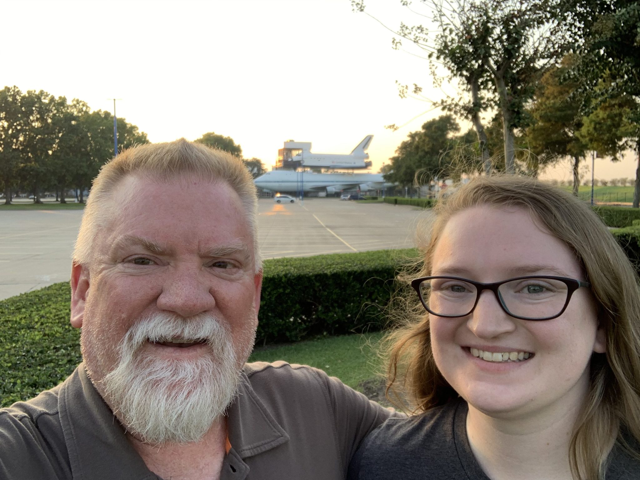 A young woman and her father take a selfie in front of Space Center Houston's 747-mounted space shuttle.