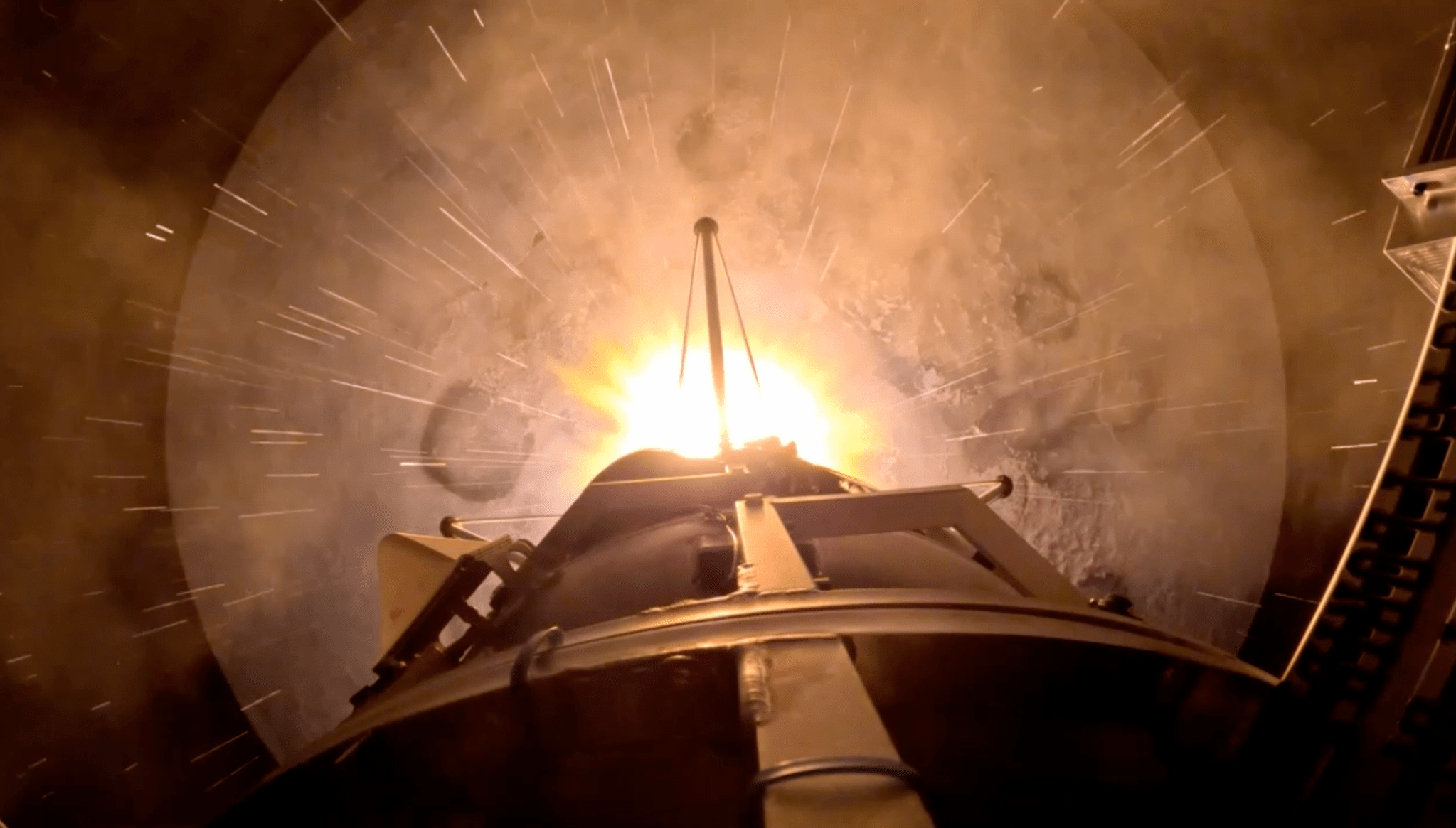 Top-down view of a rocket booster firing off a planetary surface.