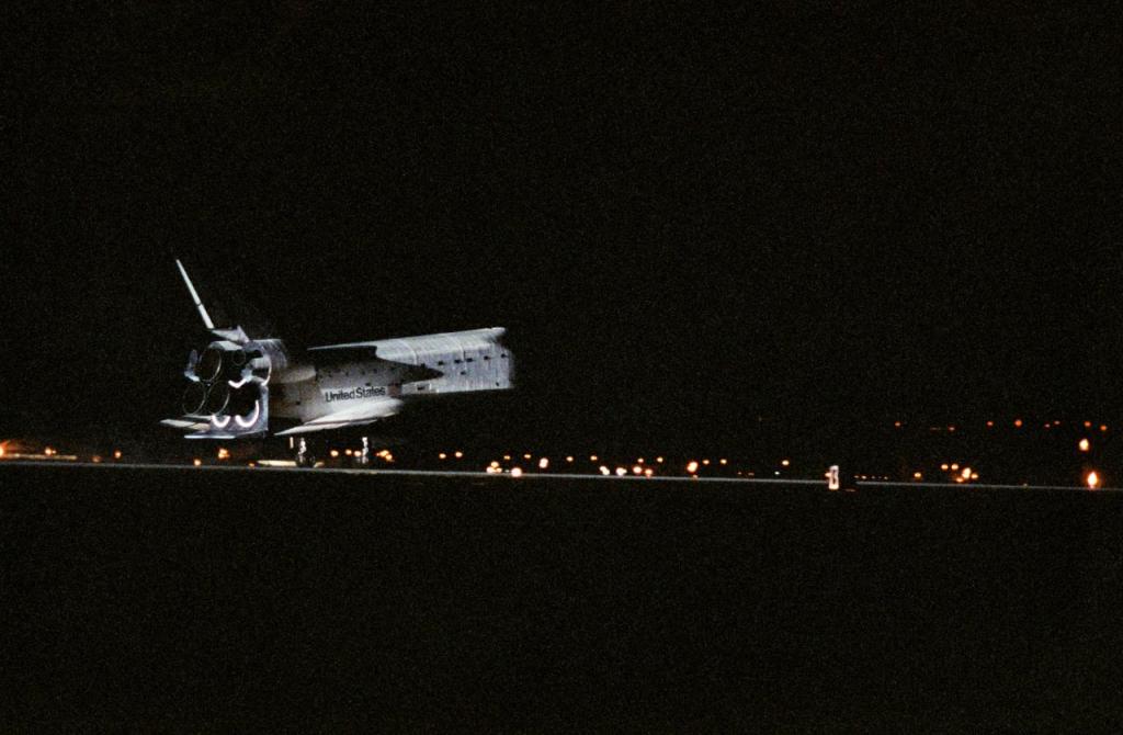 A very dark image of a space shuttle making a night landing.